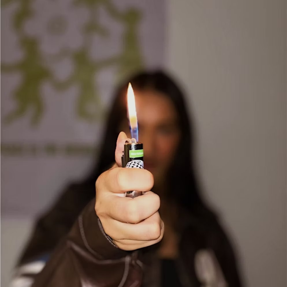Person holding a lit Herblunt lighter with a blurred background